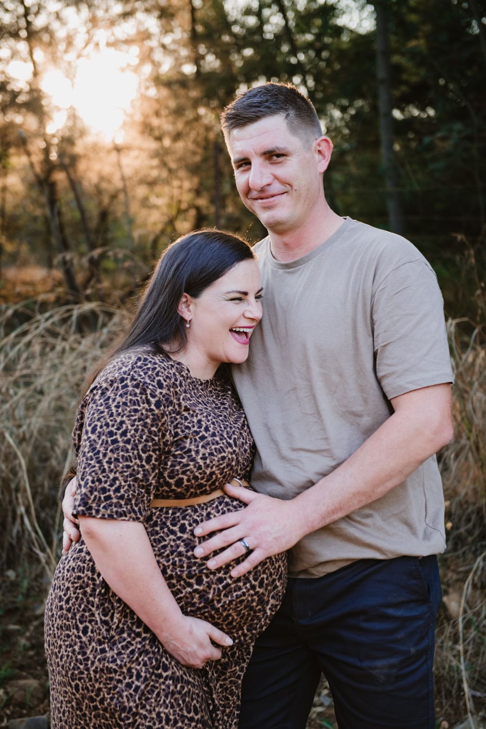 An image of mom and dad smiling during a pregnancy photoshoot.