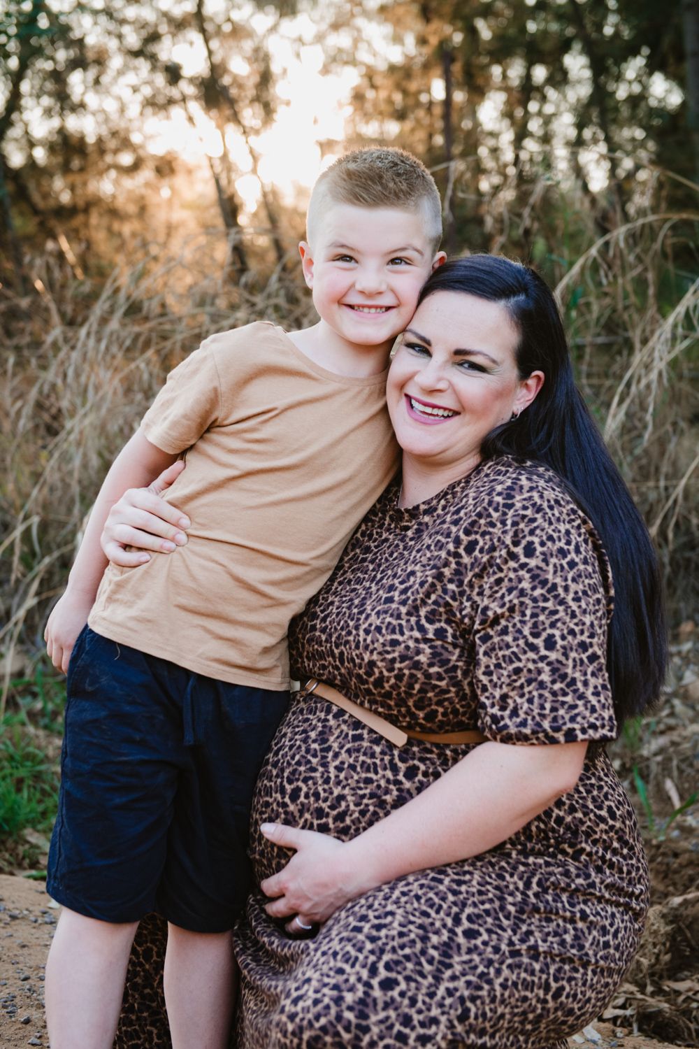 Mother and son taking a photo at her pregnancy shoot.