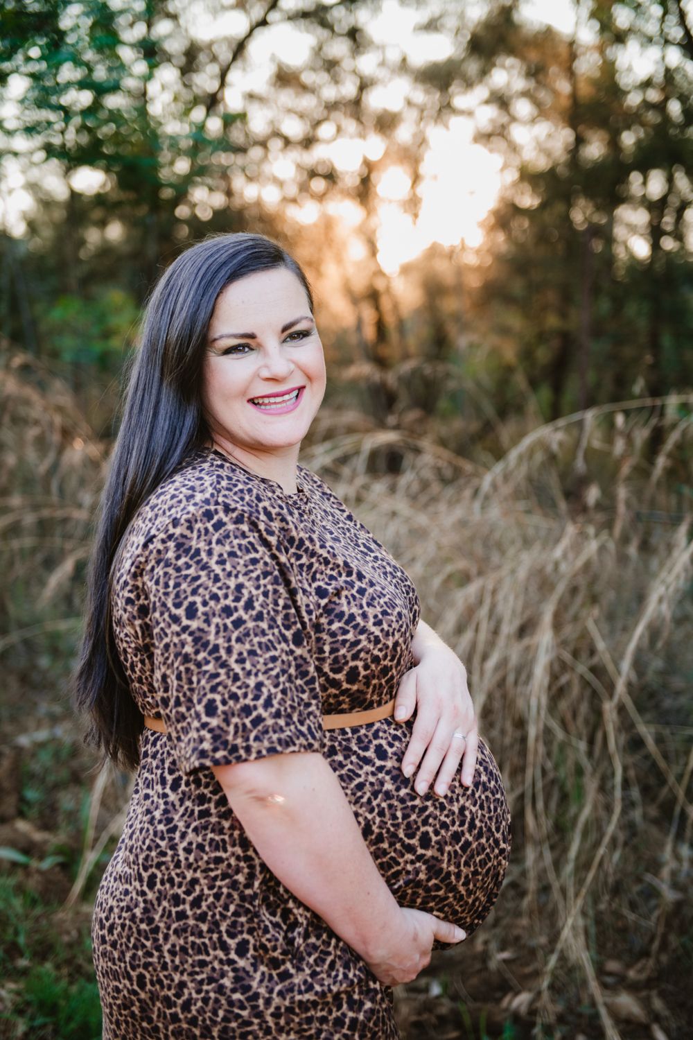 Radiant expectant mother in a long dress posing for a maternity portrait.