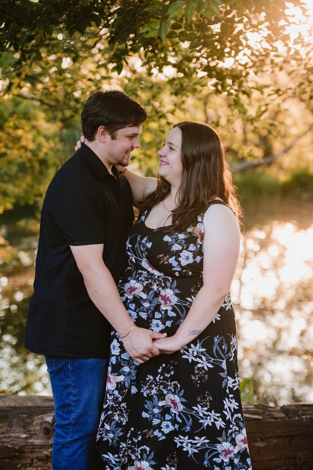 Pregnant woman and her partner smiling during a lakeside maternity session.