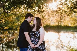 Romantic maternity shoot featuring a couple embracing near a dam.
