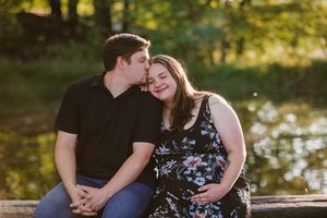 Portrait of a smiling couple with a beautiful dam backdrop for their maternity photos.