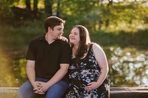 Happy parents-to-be posing by the water during their outdoor pregnancy shoot.