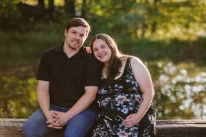 Expectant couple smiling with a scenic dam in the background during a maternity photoshoot in Gauteng