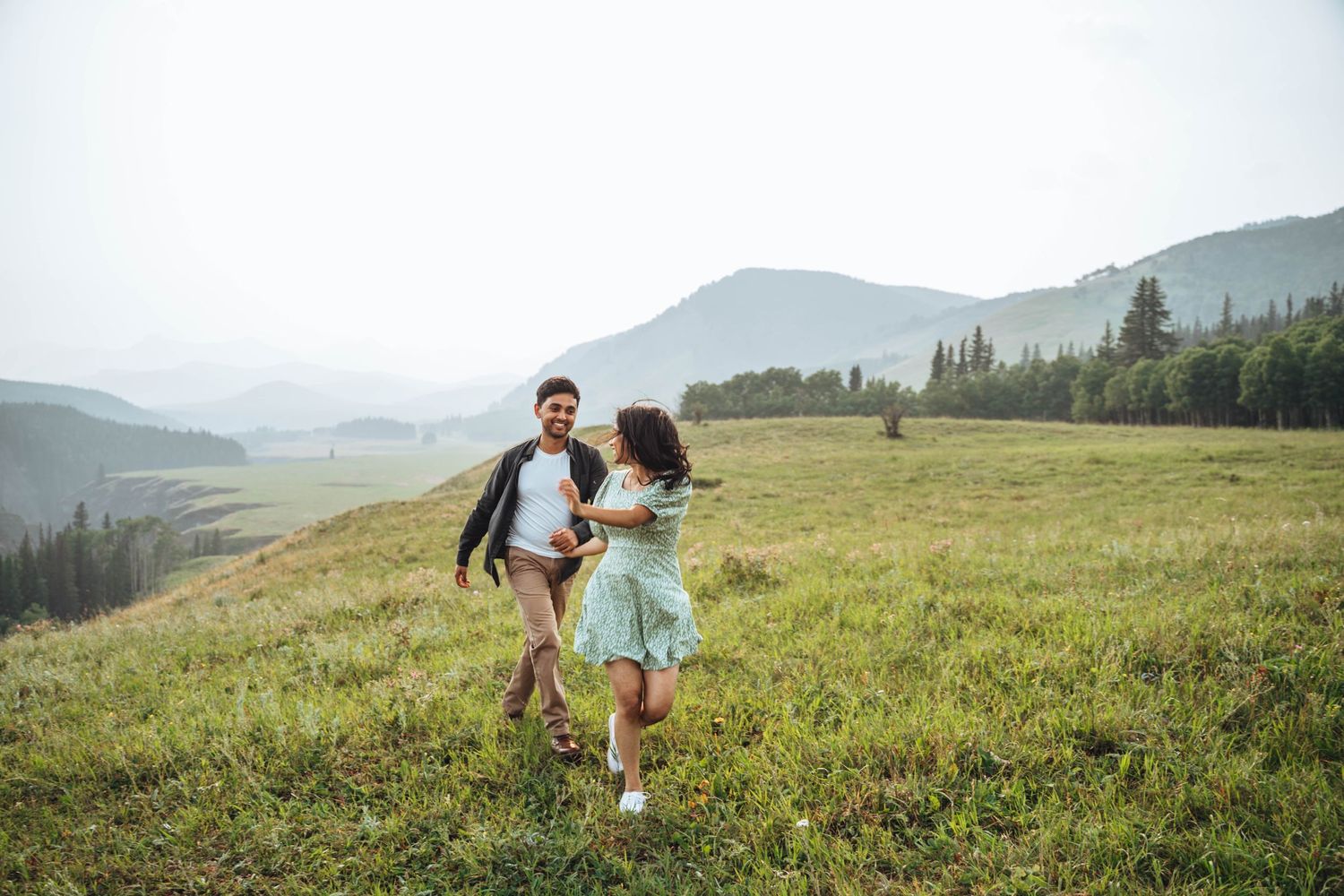 Couple running in the field. Banff engagement photography.
