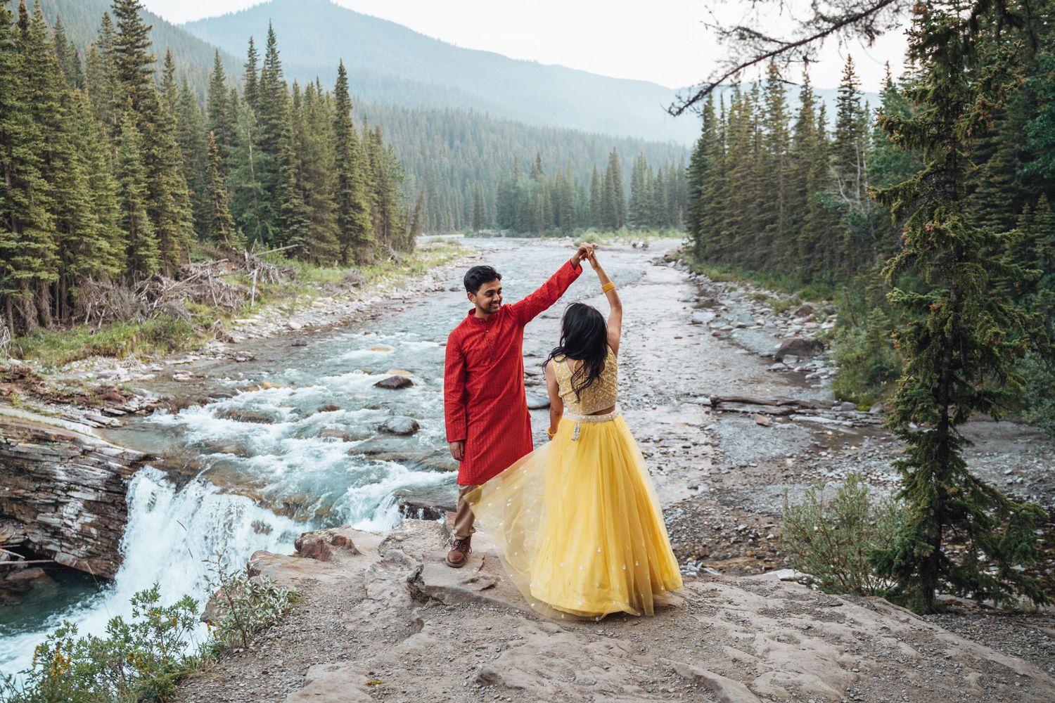 Couple dancing in front of a waterfall. Banff engagement.