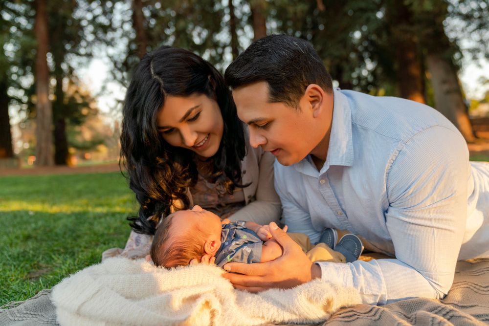 A couple gazes lovingly at their newborn baby during an outdoor photo session.