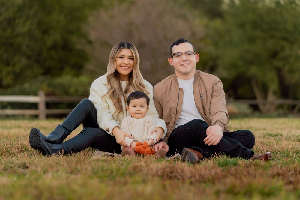 A family relaxes together on grass during a fall outdoor photo session.