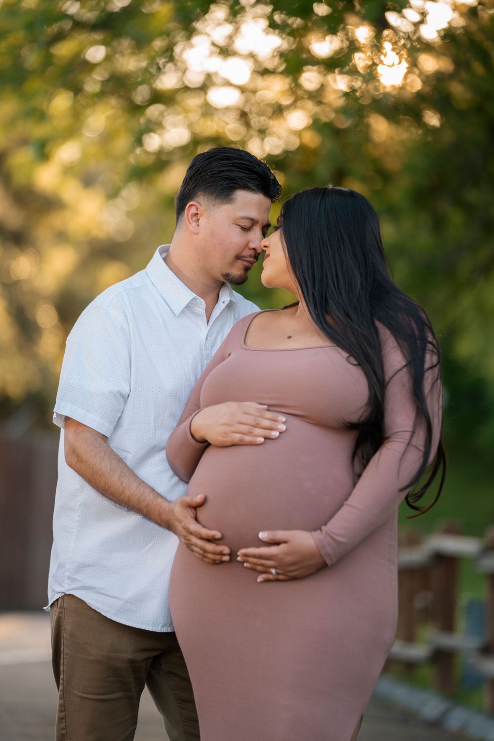 Couple embracing outdoors during sunset maternity photoshoot.