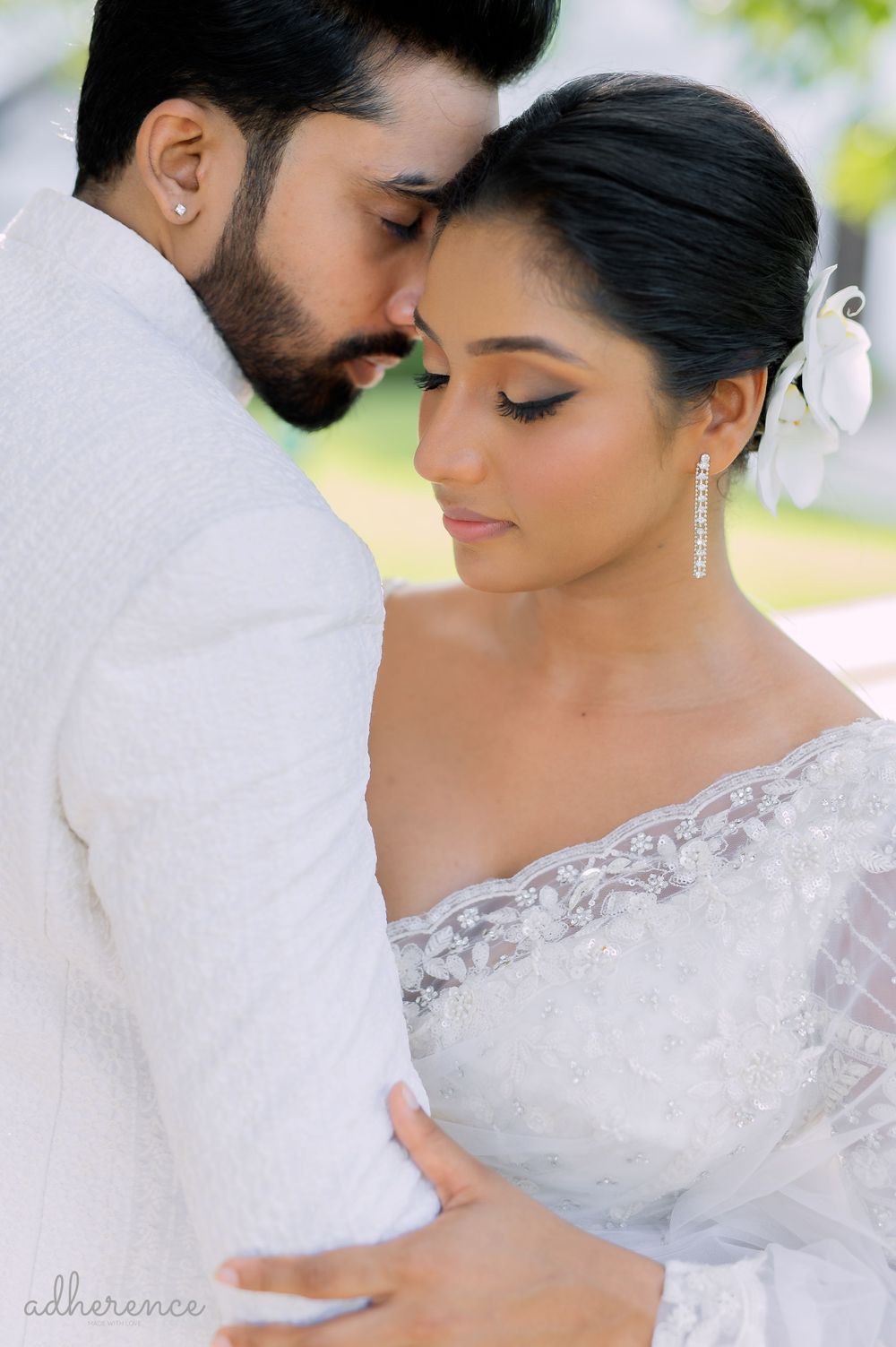 Close-up romantic wedding portrait showing tender moment between couple in white attire.