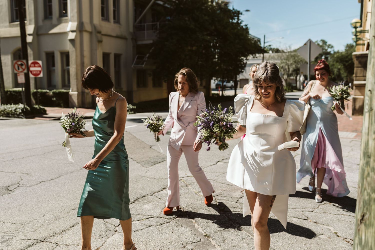 A wedding party walking and exploring the charming cobblestone streets of historic Savannah, GA on a sunny day.