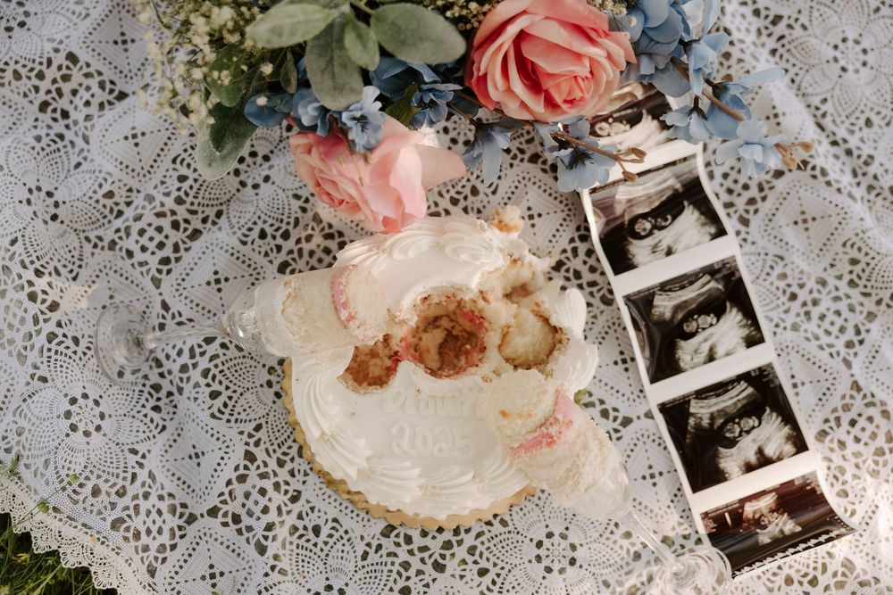 Vintage lace tablecloth decorated with pink roses and ultrasound photos creating a romantic pregnancy announcement display.