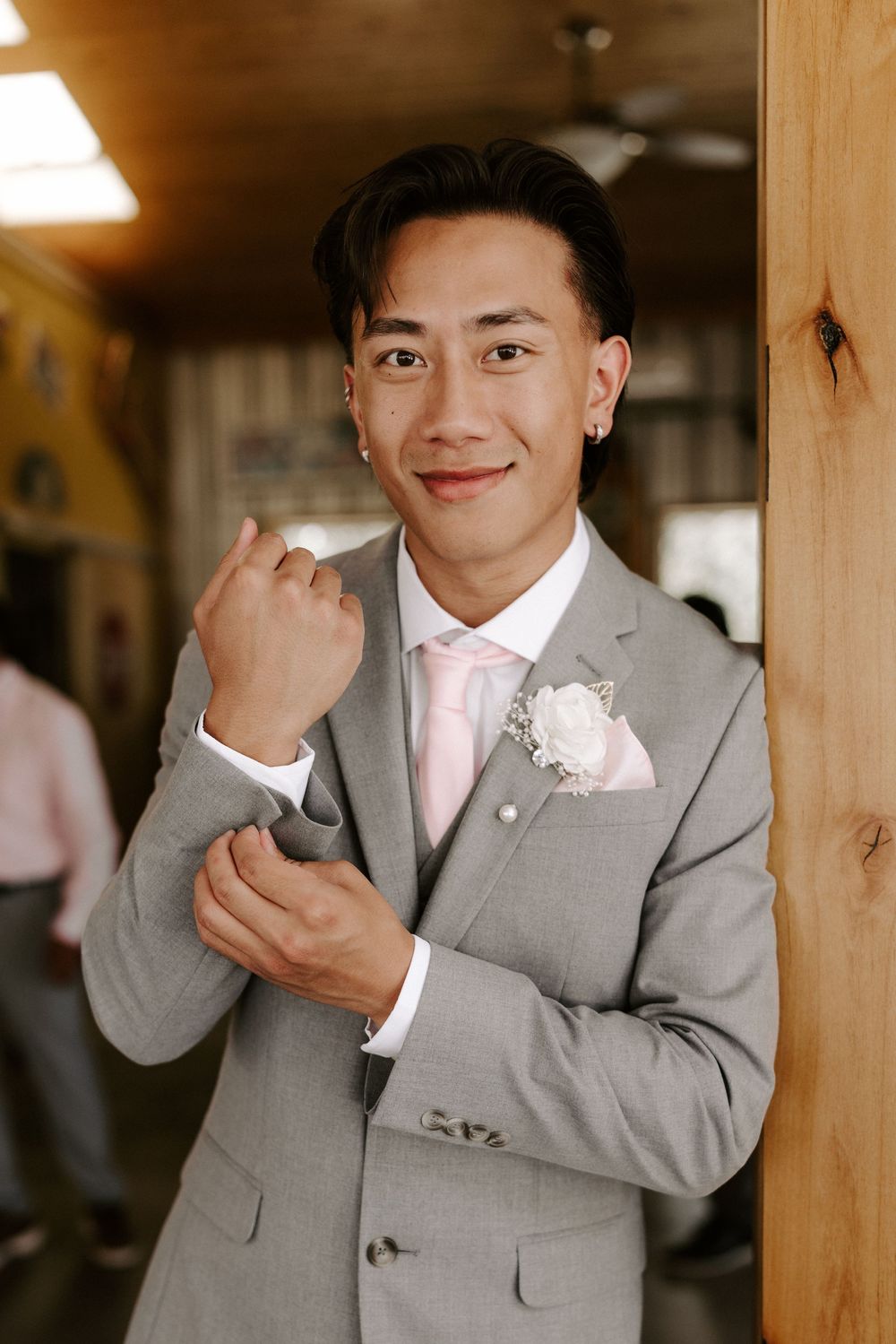 A series of photos showing a person in a light gray suit with a pink tie posing against a wooden background.