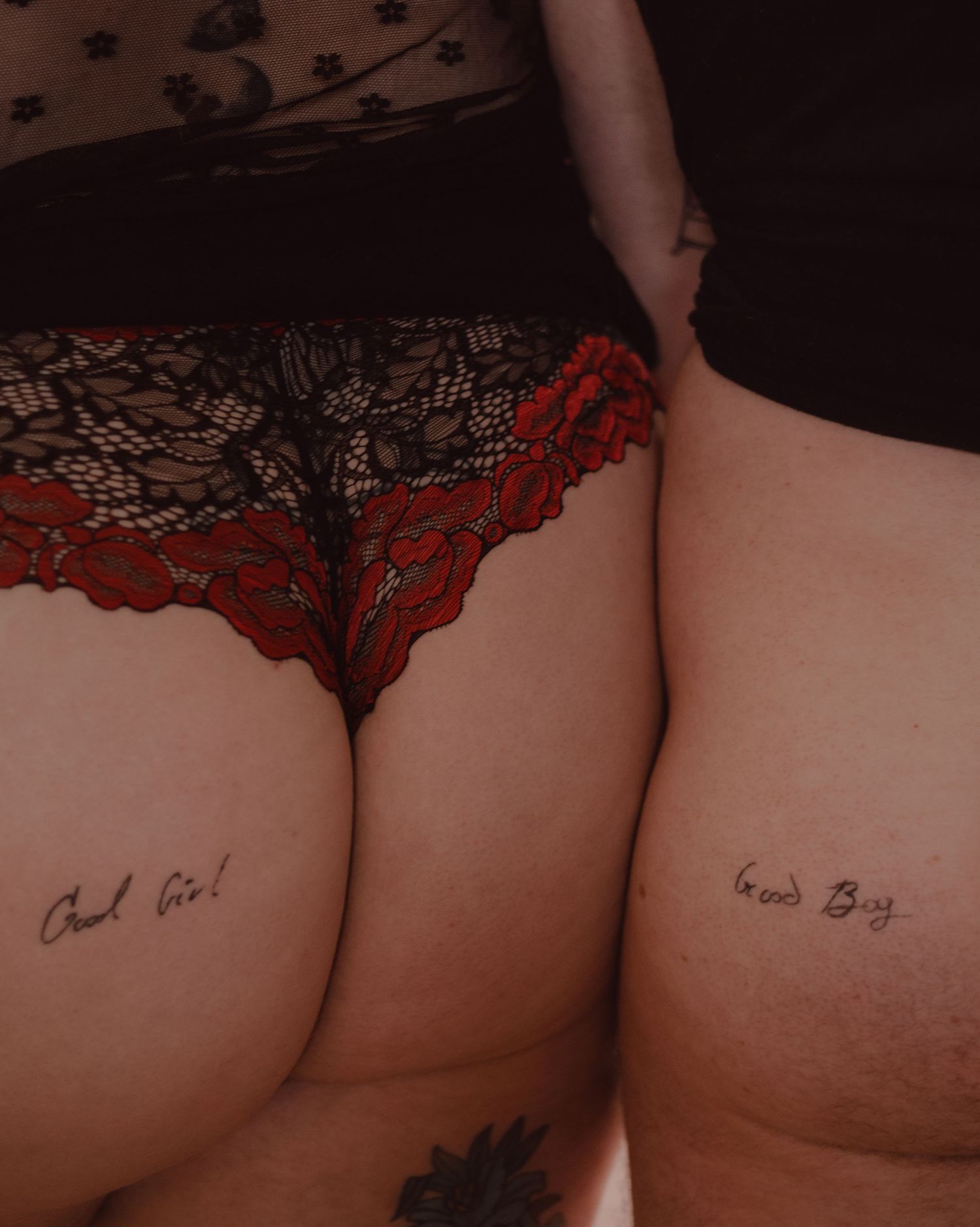 The couple pose side by side together to show off their cheeky tattoos for each other during their couple's boudoir session.