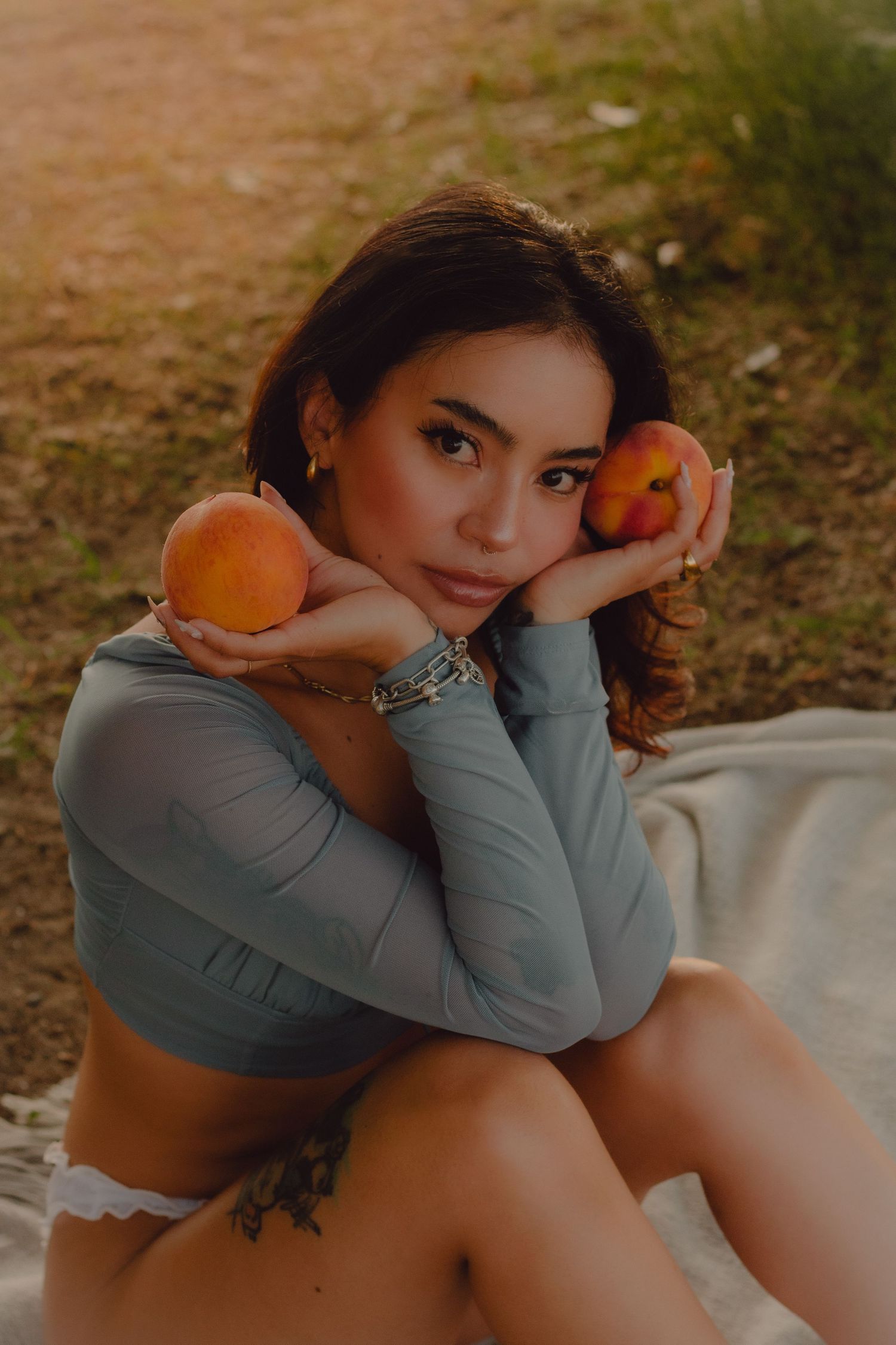Model sitting on a blanket during early morning boudoir session at the beach. Summer vibes with peaches and soft light.
