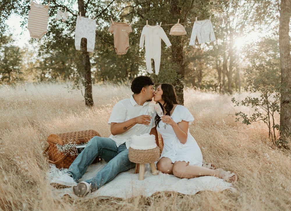 A couple relaxes together in a sun-drenched field during a romantic outdoor photoshoot at golden hour.