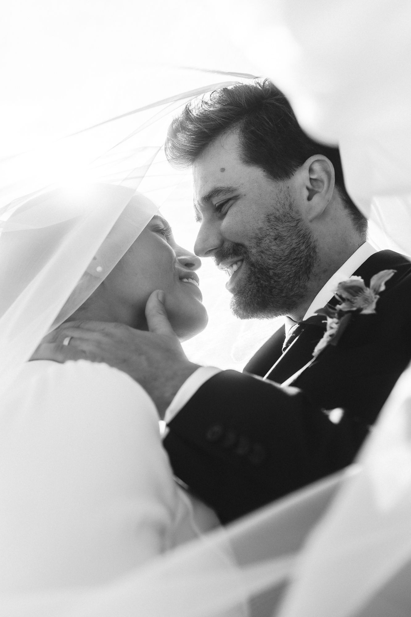 Black and white romantic wedding portraits showing intimate moments between bride and groom under flowing veil.