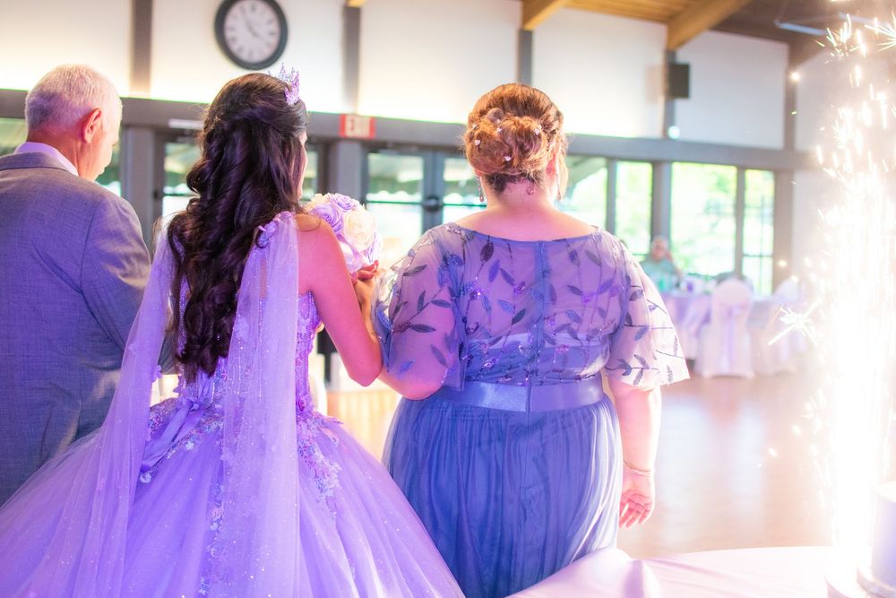 A group in formal attire gathers at an indoor event with purple lighting and elegant decor.