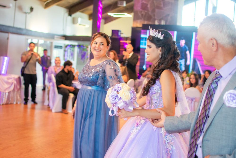 People dancing together in a bright indoor dance studio with purple lighting and wooden floors.