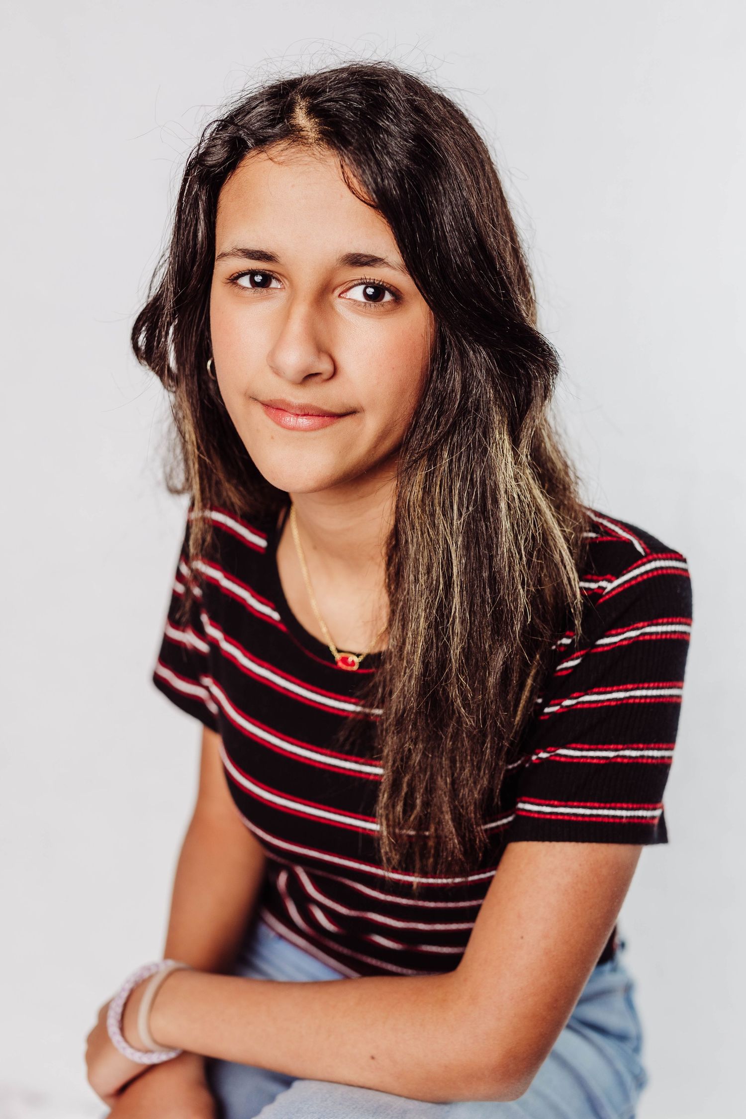 A black and white portrait of a young person wearing a striped shirt while smiling at the camera.