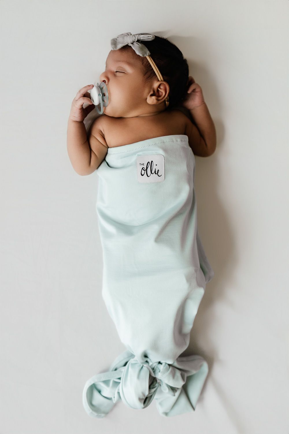 A newborn baby sleeps while wearing a mermaid swaddle at her newborn photoshoot