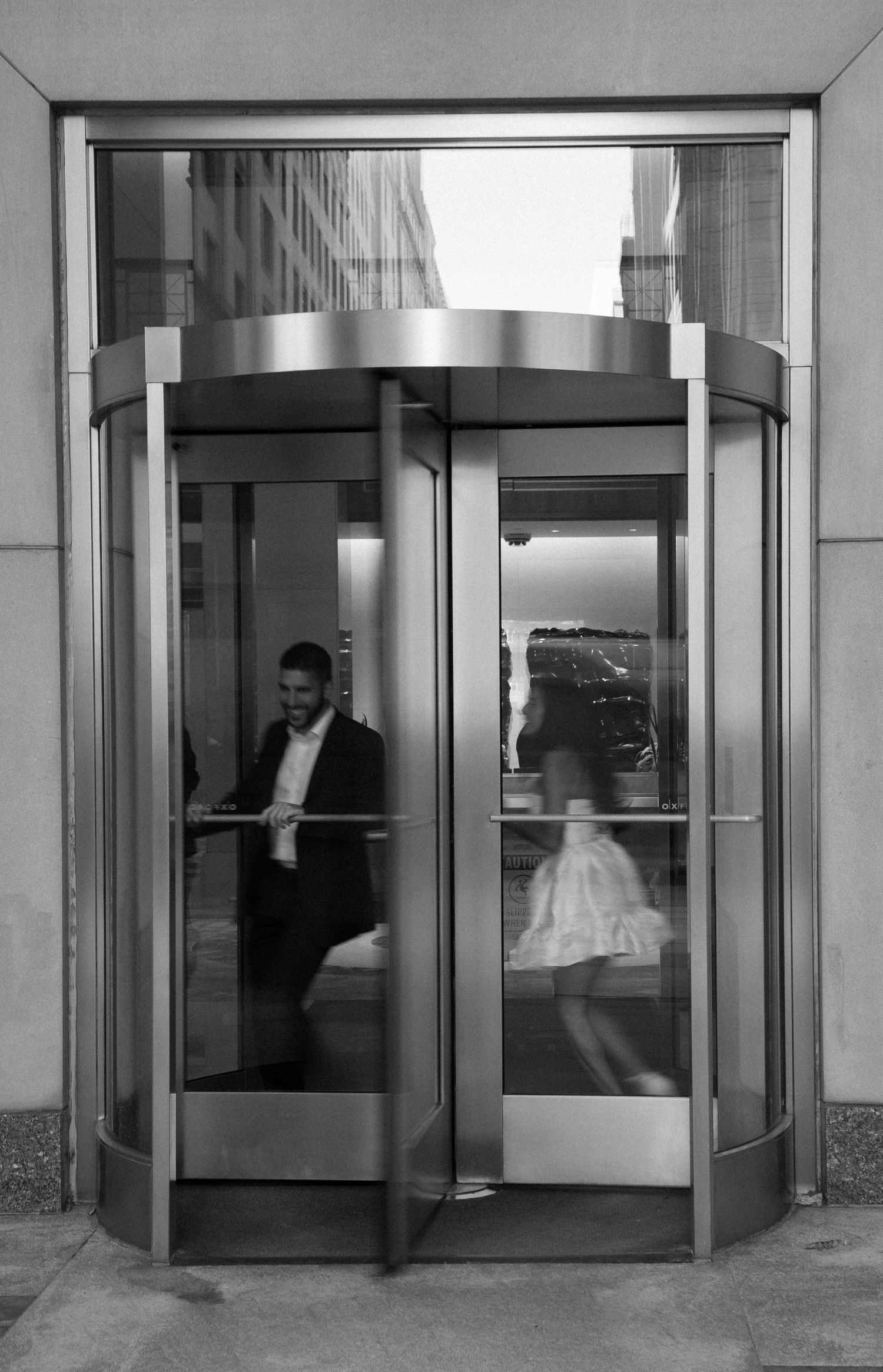 A black and white photo series showing revolving doors in an office building entrance with people passing through in Boston.