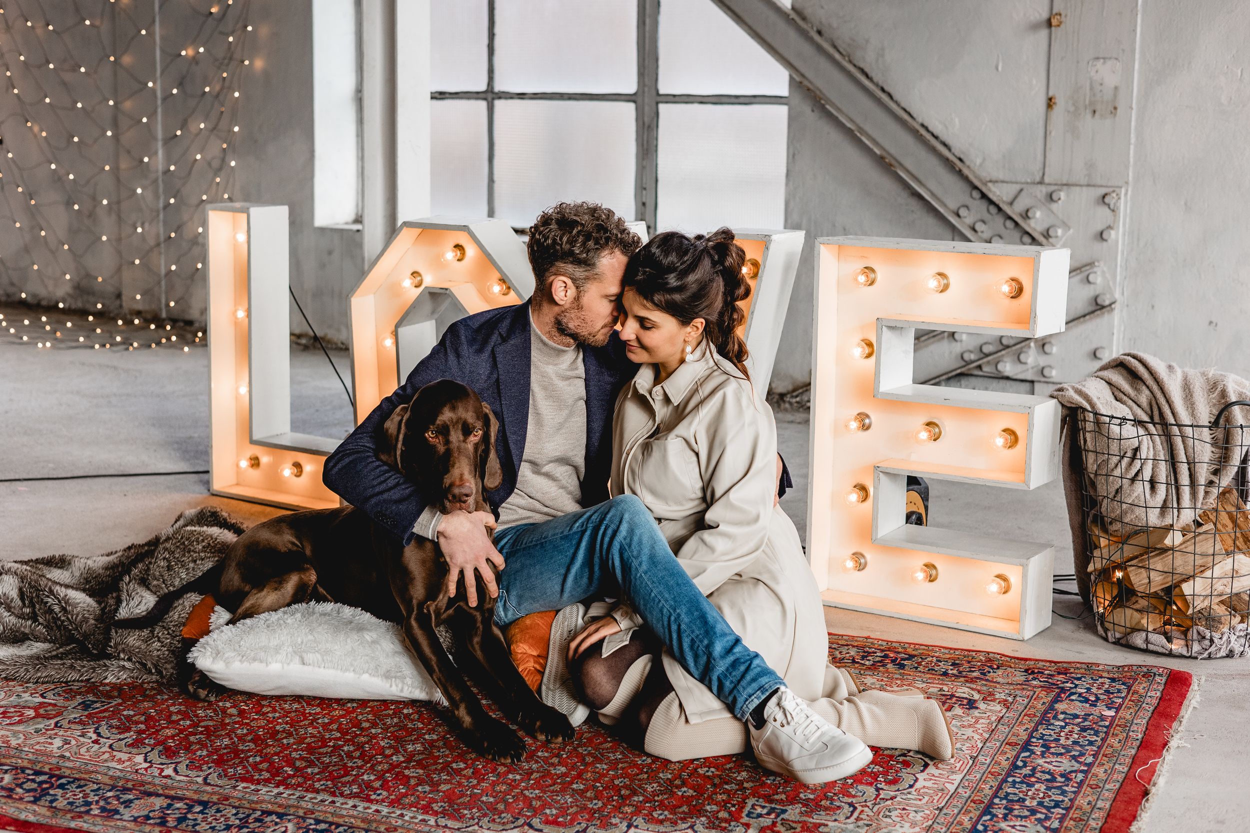 Cozy indoor photo session with fairy lights and decorative pumpkins on oriental rugs.