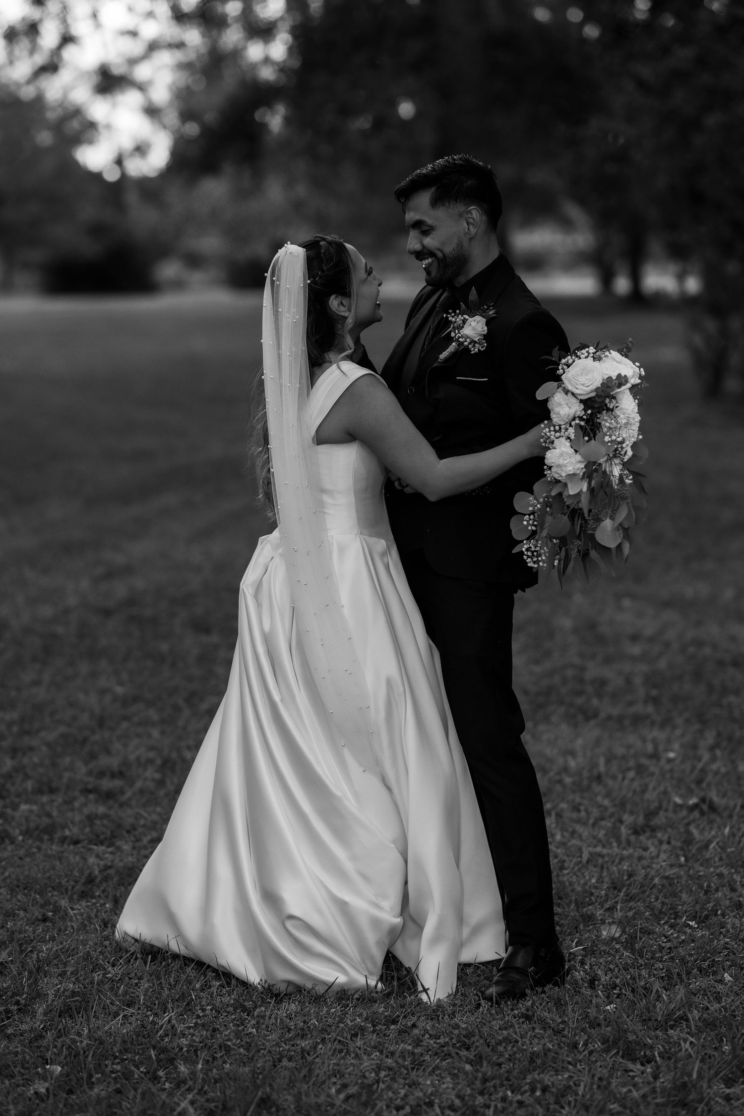 Black and white wedding photography session in a garden setting with flowing white dress.