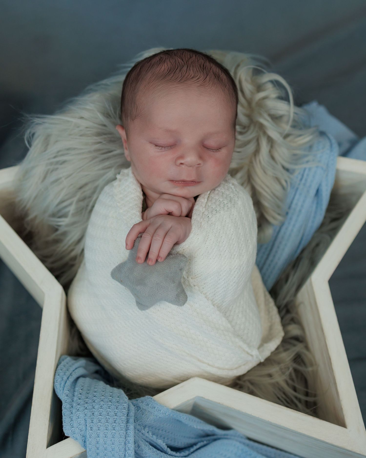 Newborn baby wrapped in neutral tones during a professional studio session in Attica MI