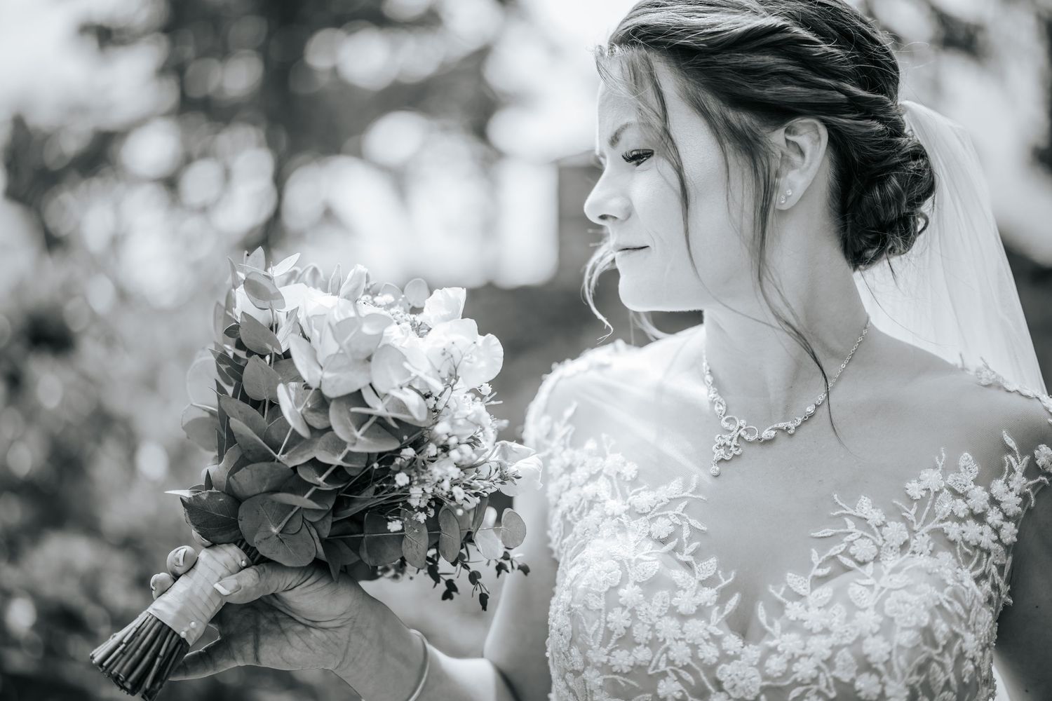 Black and white photo of a bride looking at flowers