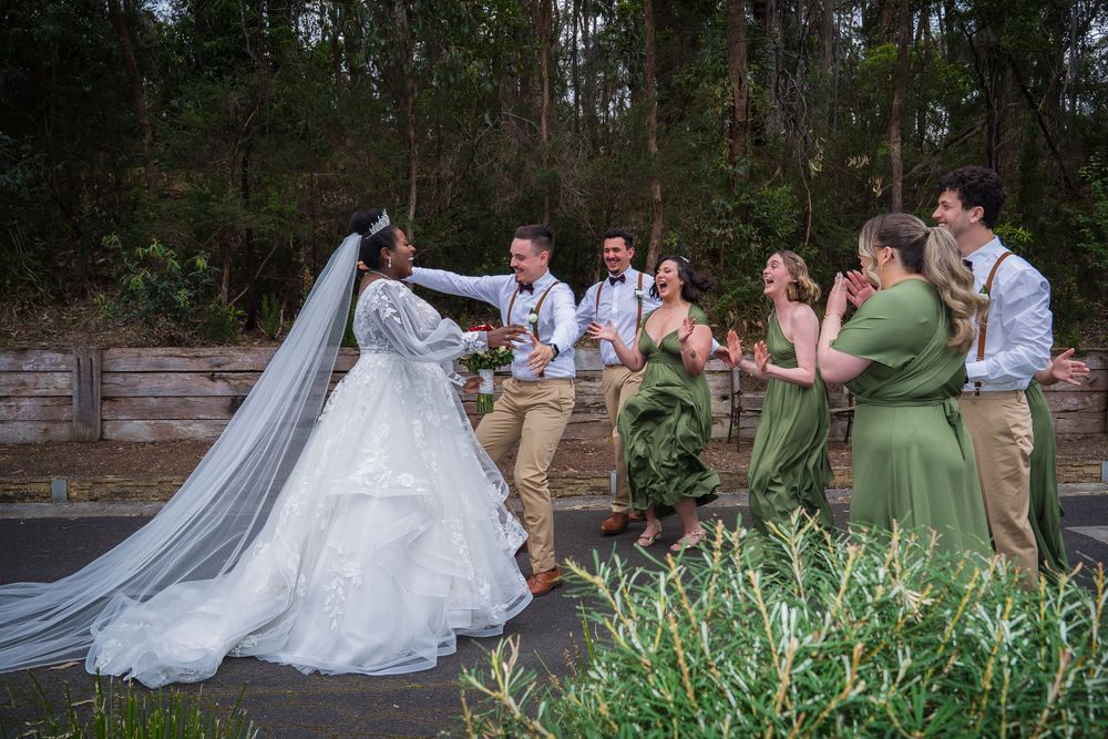 Wedding party poses together on stone steps in an outdoor garden setting.