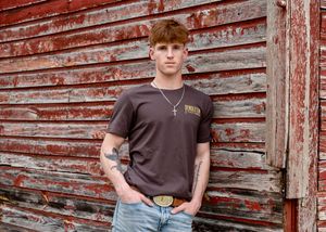 Casual outdoor portrait against rustic red barn siding.