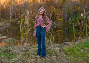 Golden sunset light illuminates tall grass and trees in an autumn meadow landscape.