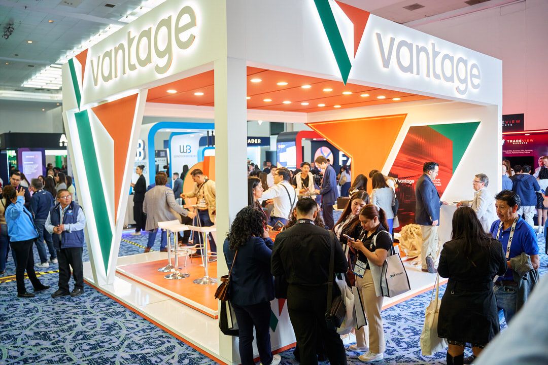 Equipo comercial de Vantage explicando servicios financieros a visitantes en su stand.