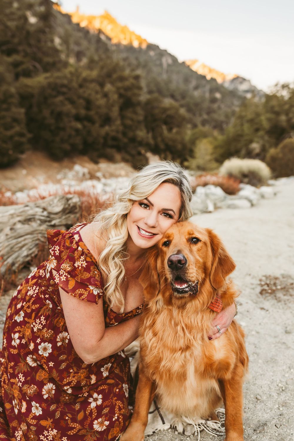 Golden retriever and companion pose together in desert landscape during golden hour sunset.