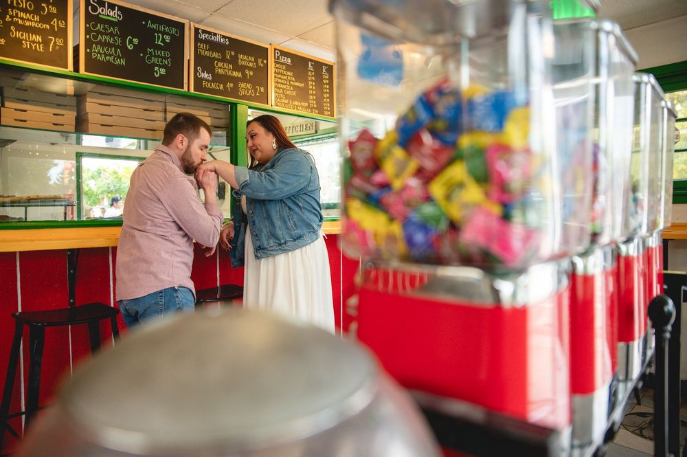 Two people share a quiet moment at a casual restaurant counter with colorful candy machines in the background.