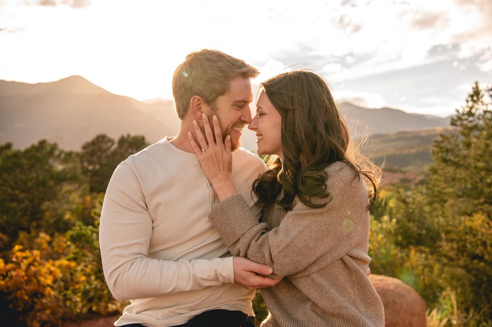 Romantic couple embraces during golden hour sunset in mountain landscape with warm autumn lighting.