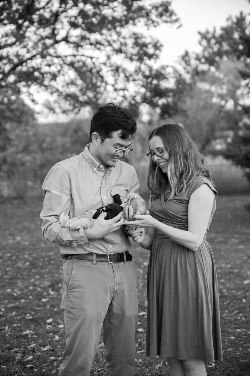 A couple shares a playful moment together in a park setting with autumn leaves scattered on the ground.