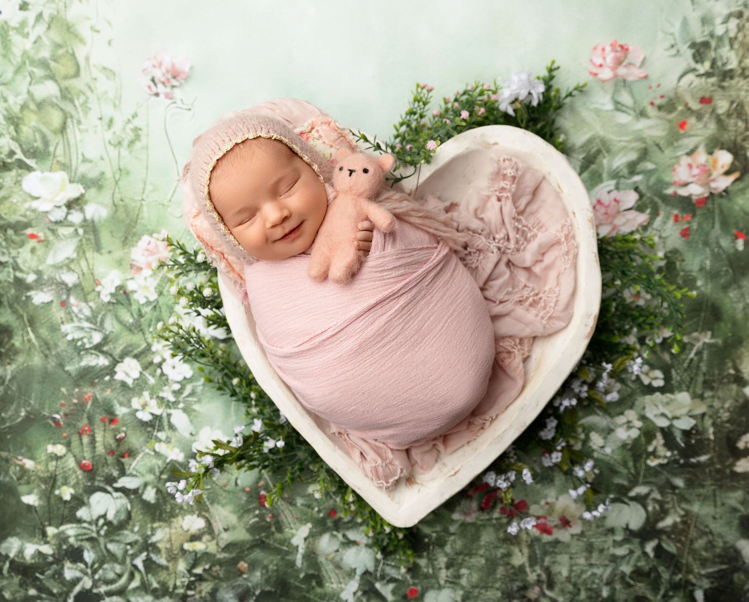 Lakes Region NH newborn photography of a sleeping baby wrapped in pink, fine art studio portrait with floral details and soft light.