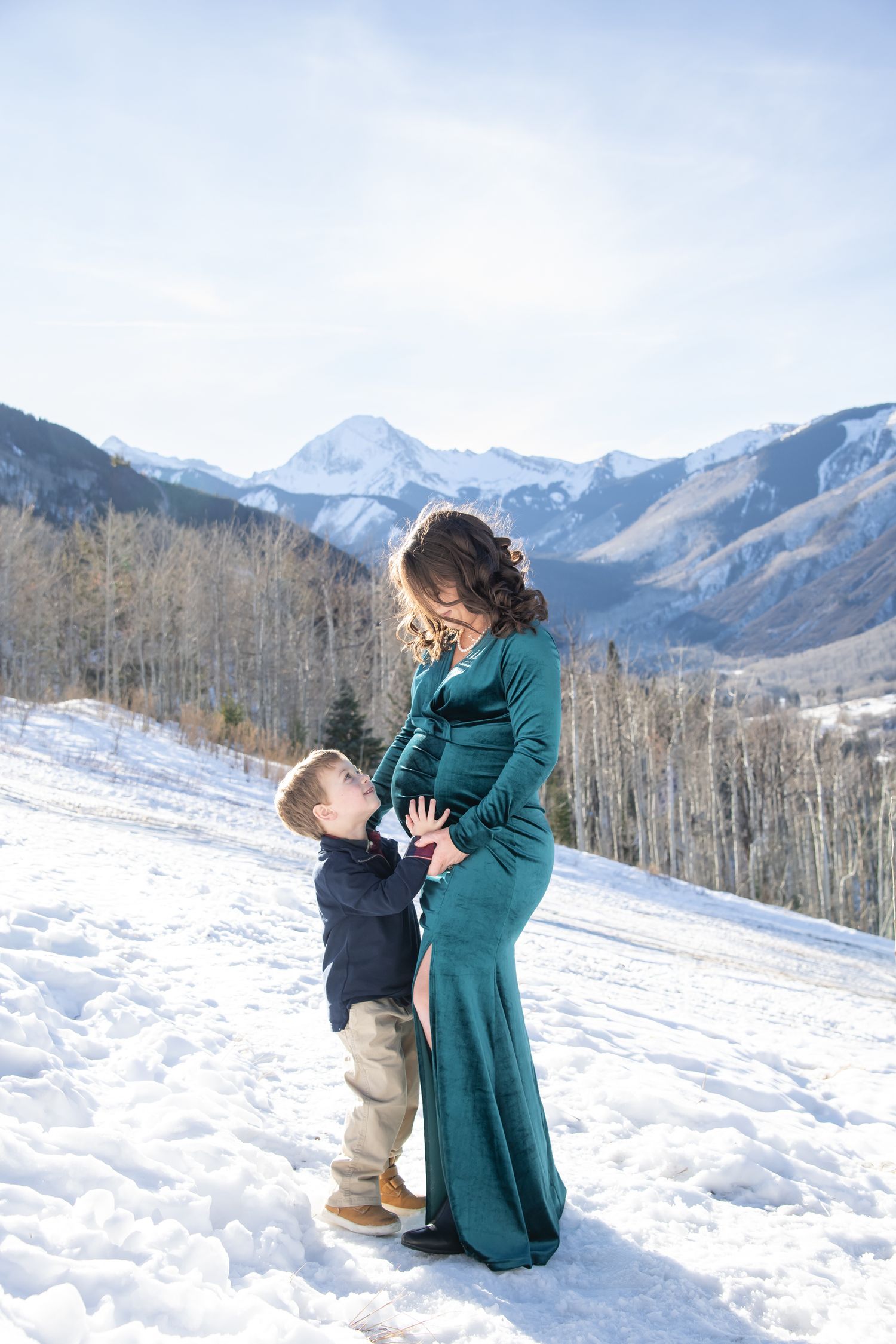 A sweet moment with mother and son during winter maternity photo session in Snowmass Colorado with snowy mountain peaks