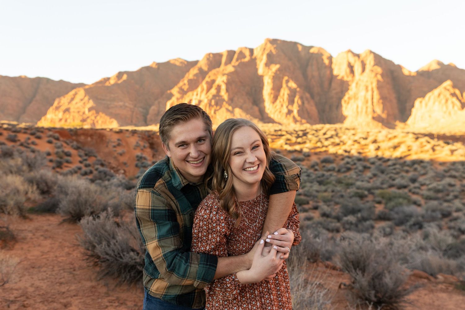 St. George engagement photographer captures couple with glowing red desert background at golden hour.
