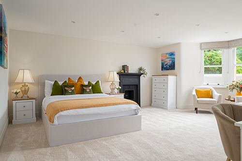 A bright white bedroom with vaulted ceilings features built-in storage, window seating, and natural lighting.