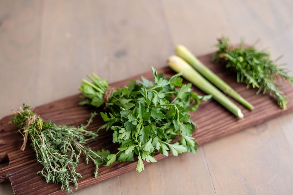 Fresh herbs arranged on a rustic wooden cutting board.