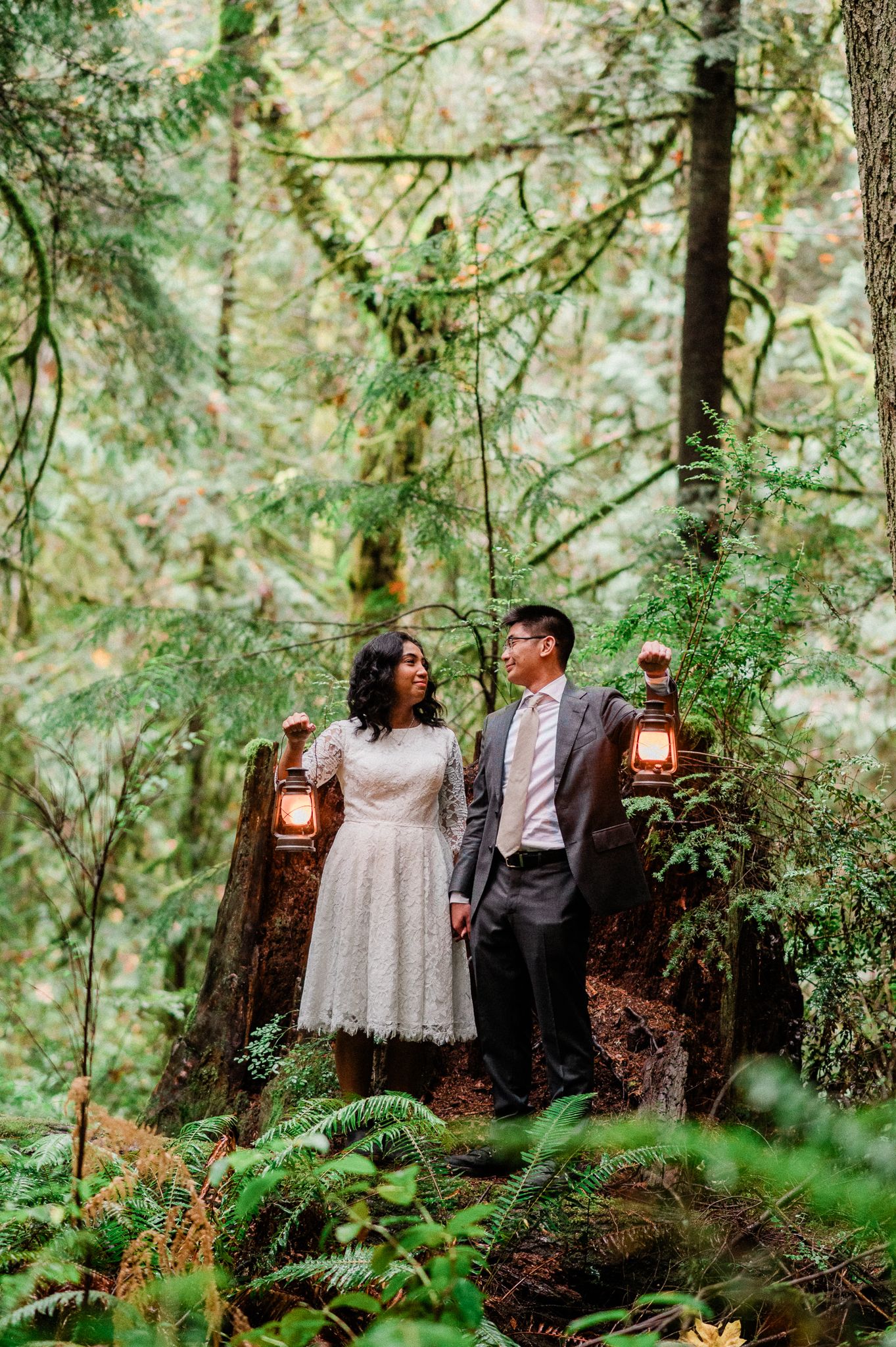 Bride and groom standing in the Grand Forest West on Bainbridge Island while holding lanterns.