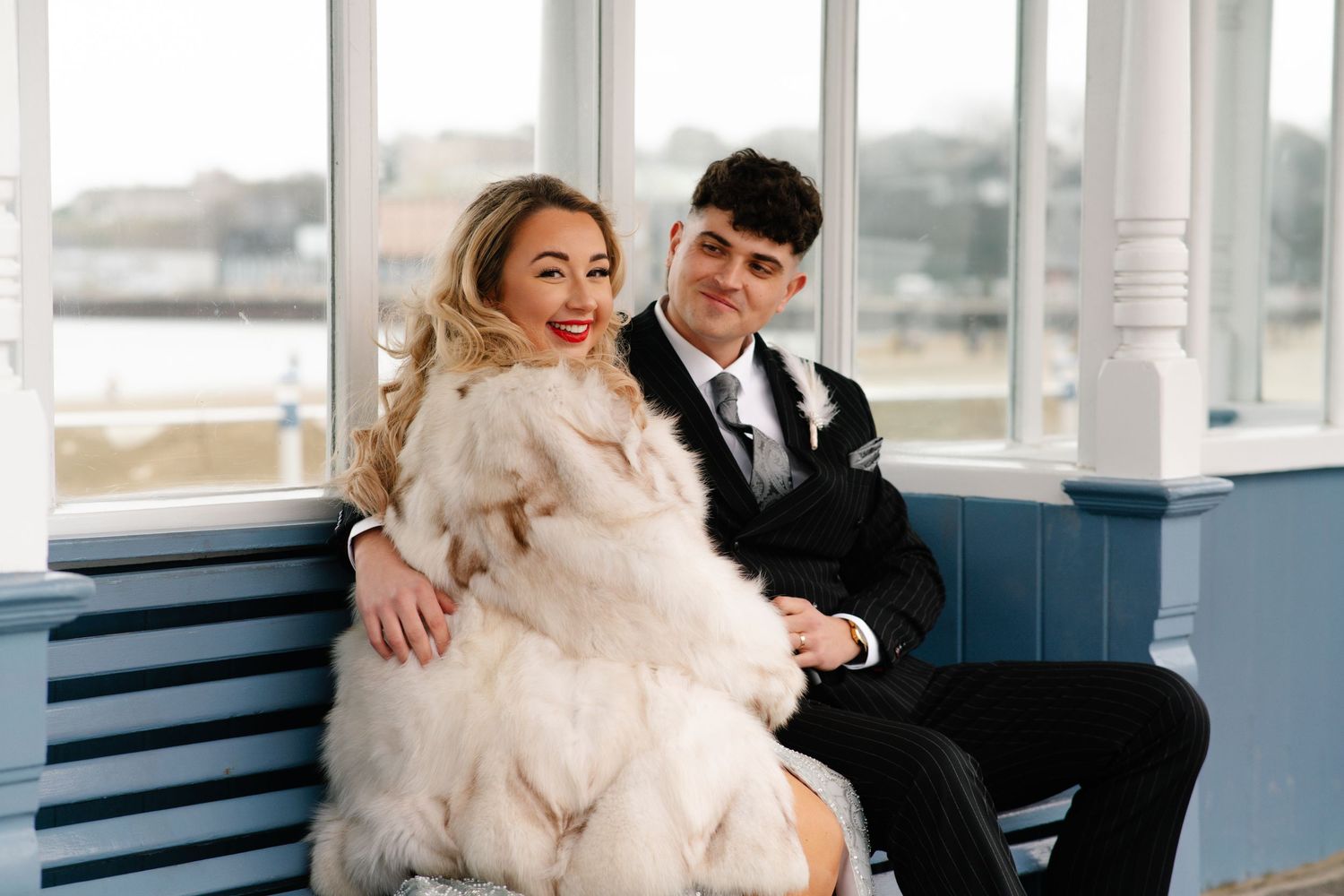 Bride and groom sitting together at a bus stop on Weymouth promenade during their New Year’s Eve wedding
