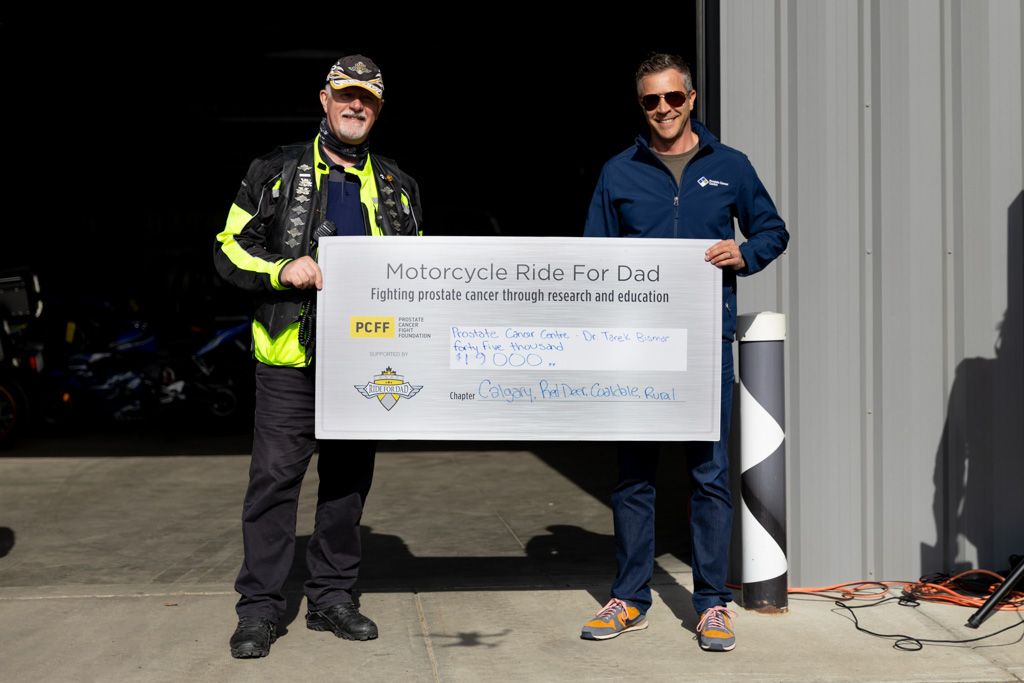 Two people stand holding a large presentation check at a fundraising event.