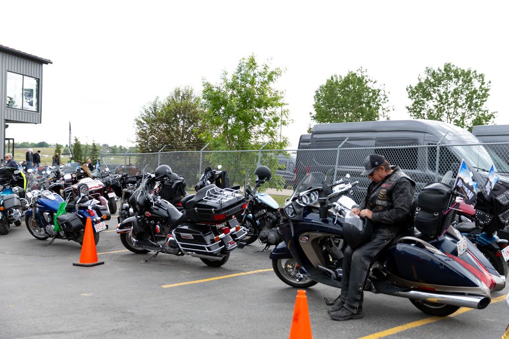 Row of parked motorcycles lined up in a parking lot with orange traffic cones visible.