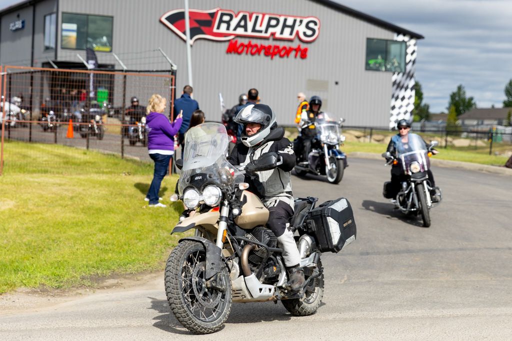 Motorcycles lined up outside Ralph's Motorsports dealership on a cloudy day.