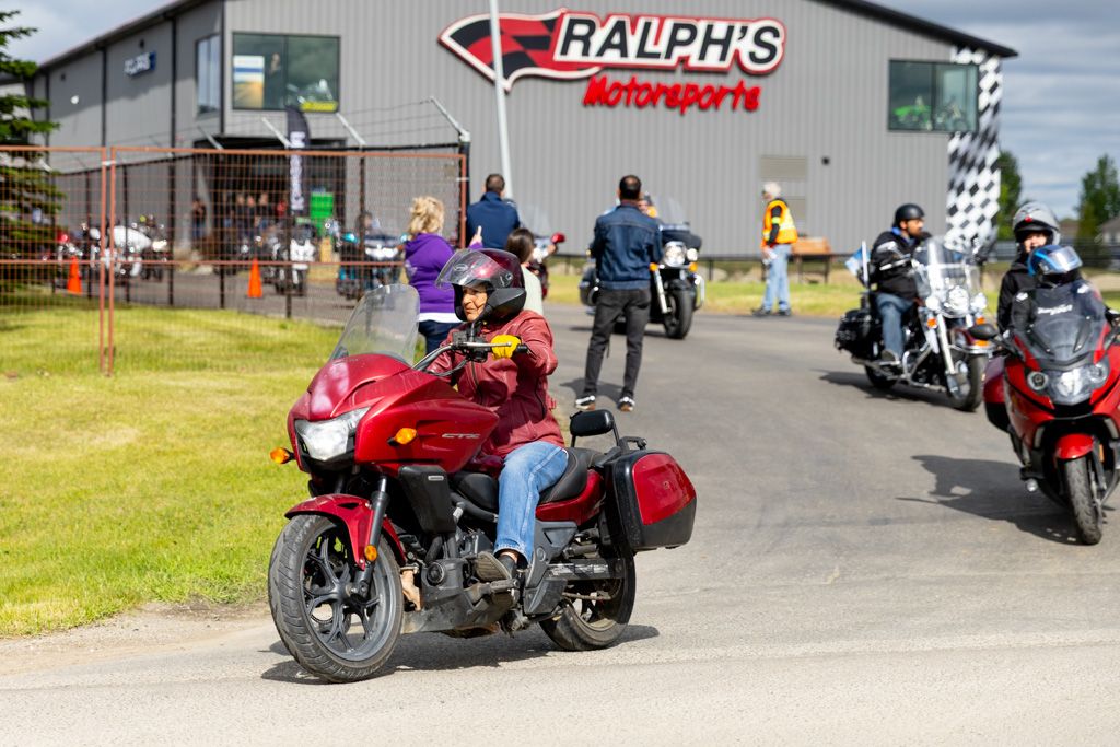 Motorcycles parked outside Ralph's storefront with red signage on a cloudy day.