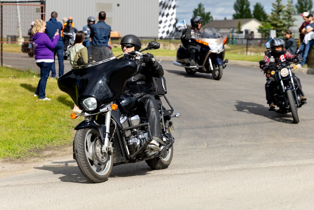 Multiple motorcycles parked in formation at an outdoor event with a checkered flag visible.